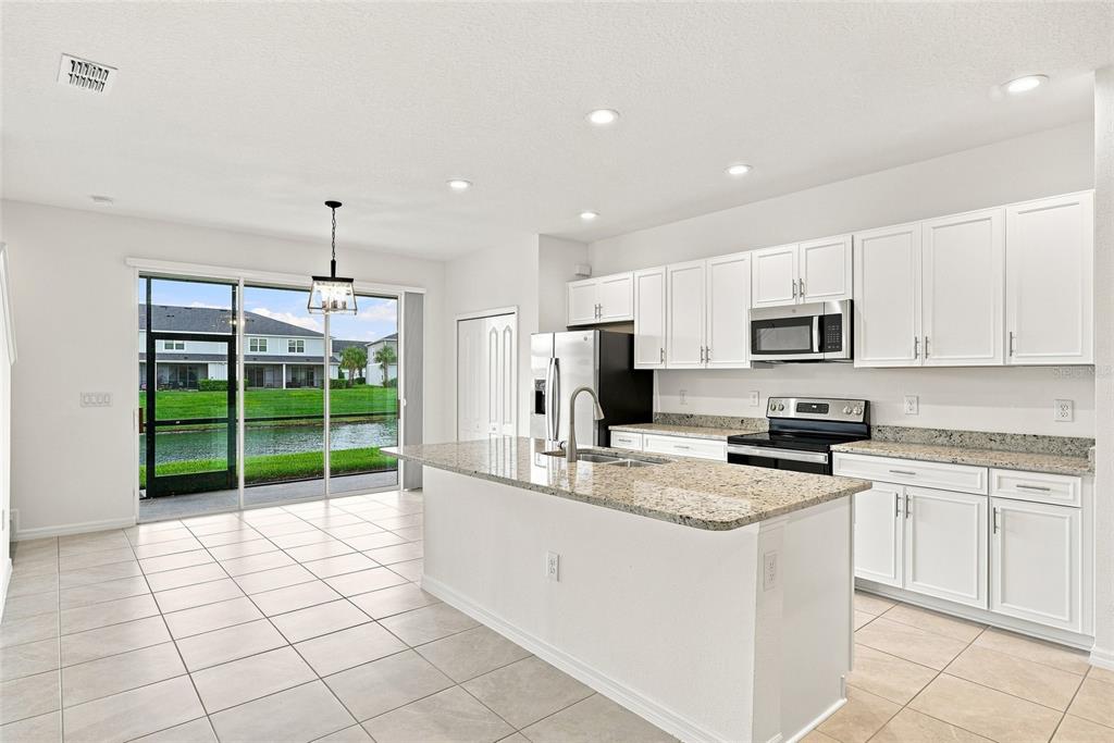 A kitchen with white cabinets, granite countertops, and a center island overlooking a pond — 8514 CANYON CREEK TRAIL, PARRISH, FL