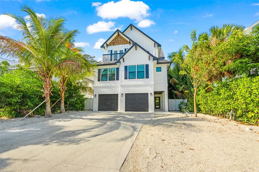 A white three-story house with a two-car garage and a gravel driveway — 211 GRANT DRIVE, SARASOTA, FL