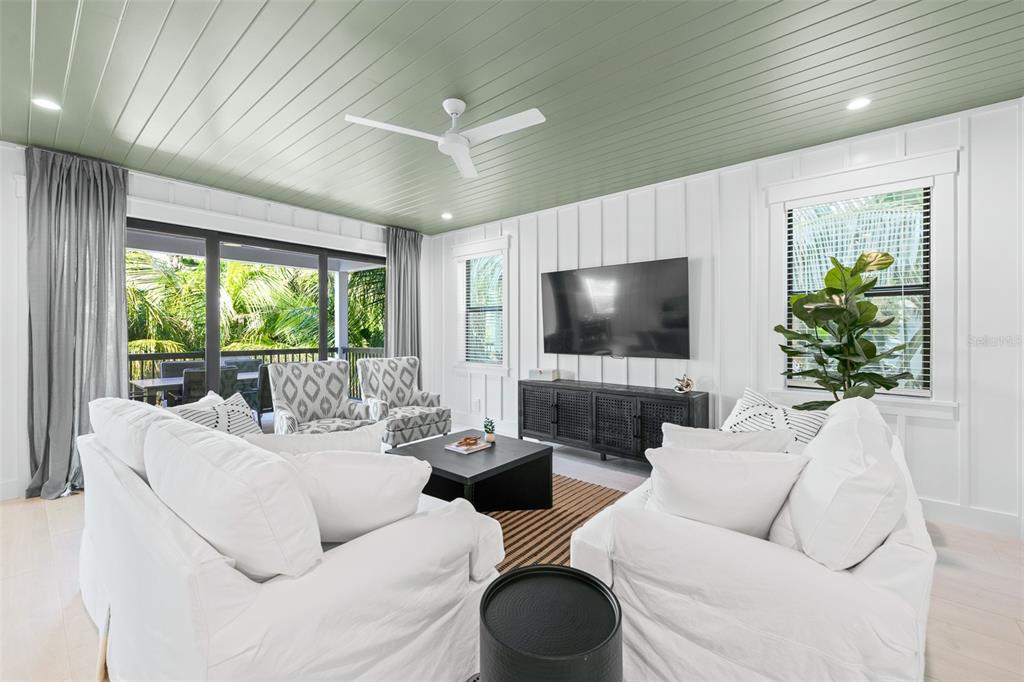 A living room features white board-and-batten walls, a green plank ceiling, and a sliding glass door — 211 GRANT DRIVE, SARASOTA, FL