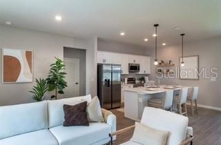 A modern open-concept kitchen with white cabinetry and an island overlooks a living room area — 3859 SW 169TH LANE ROAD, OCALA, FL