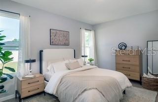 A bedroom features a bed with white bedding, a wooden nightstand, and a wooden dresser — 3859 SW 169TH LANE ROAD, OCALA, FL