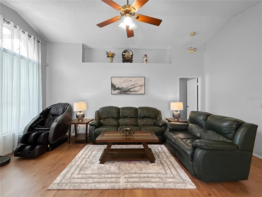A living room features dark leather sofas, a massage chair, and a central coffee table — 3228 RUNNING BEAR WAY, KISSIMMEE, FL