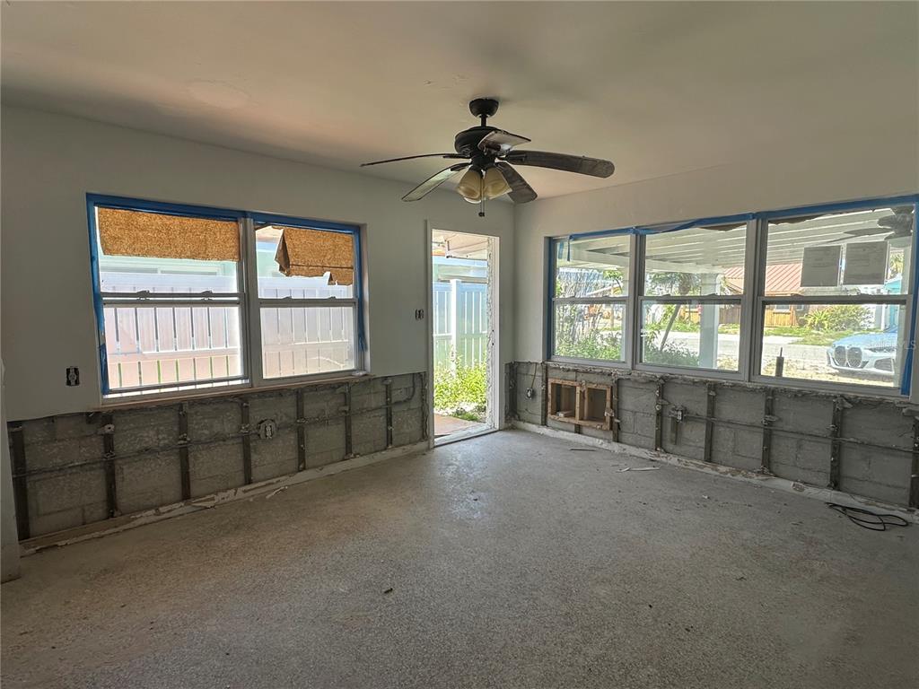 An unfinished room with exposed concrete block walls, metal furring strips, and large windows — 13434 1ST ST E, MADEIRA BEACH, FL