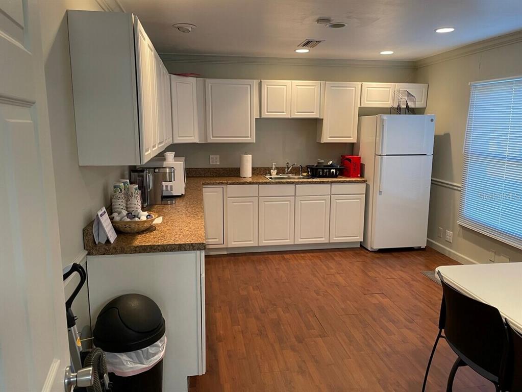A kitchen features white cabinets, speckled countertops, a white refrigerator, and wood-look flooring — 385 E WASHINGTON STREET, STARKE, FL