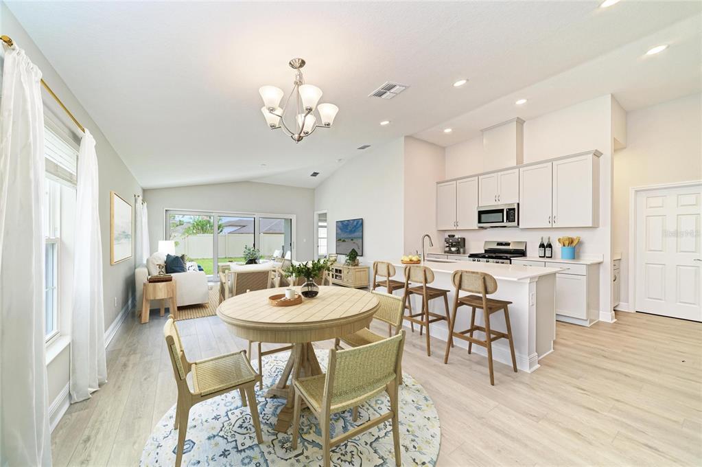 An open-concept kitchen and dining area with light wood floors, white cabinetry, and a round table — 12365 OAK  HILL WAY, PARRISH, FL