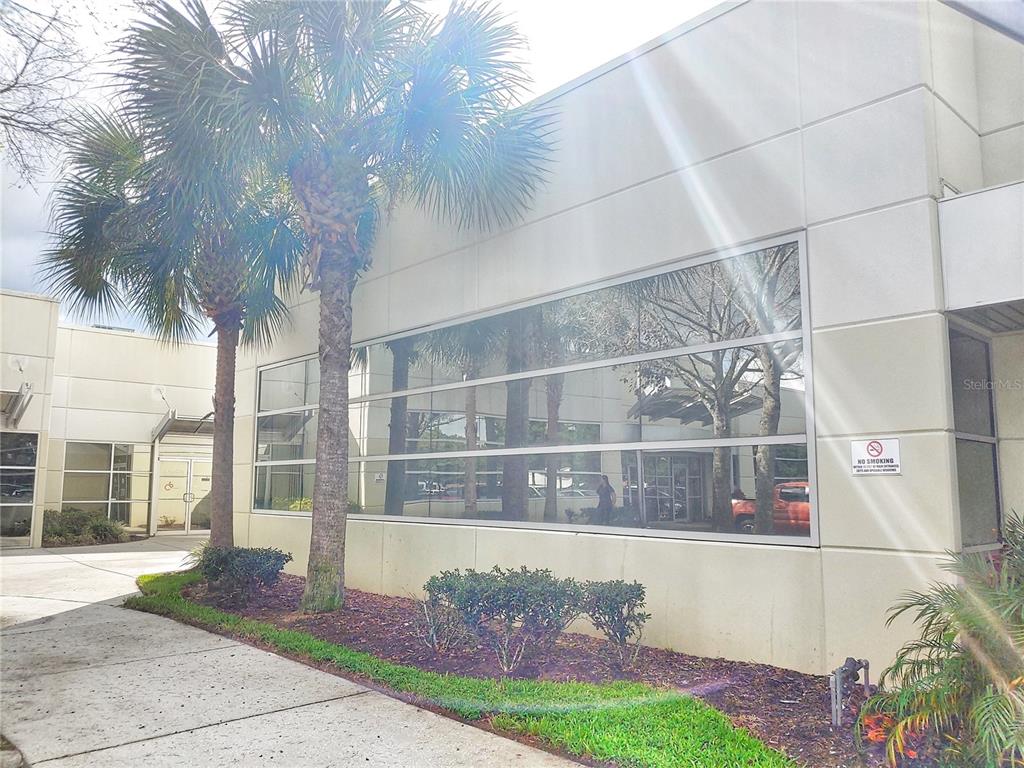 The exterior of a commercial building features a large glass window and palm trees — 8810 COMMODITY CIRCLE UNIT 17D, ORLANDO, FL
