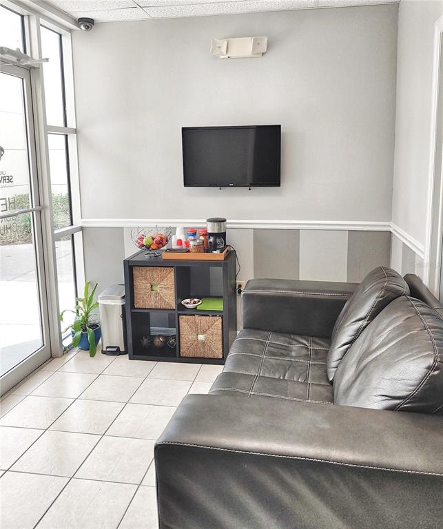 A waiting area features a black leather sofa, a television, and a coffee station — 8810 COMMODITY CIRCLE UNIT 17D, ORLANDO, FL