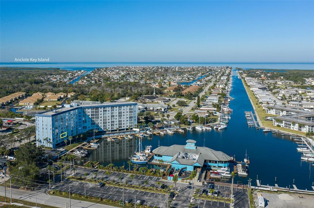 An aerial view shows a multi-story apartment building next to a canal and marina — 4939 FLORAMAR TERRACE UNIT 312, NEW PORT RICHEY, FL