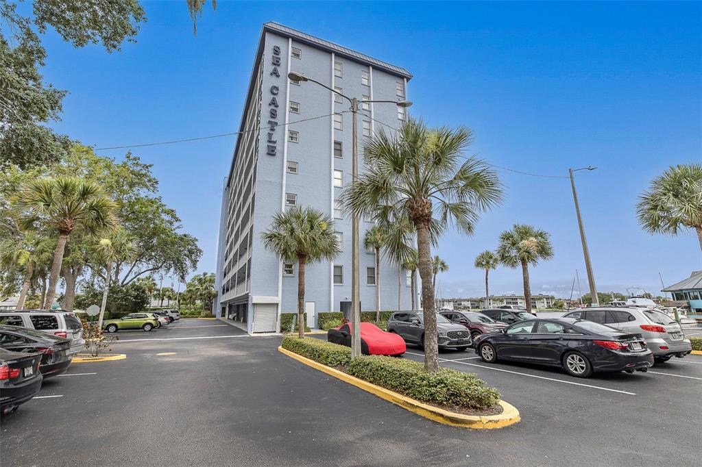 A multi-story blue apartment building named Sea Castle stands above a parking lot with cars — 4939 FLORAMAR TERRACE UNIT 312, NEW PORT RICHEY, FL
