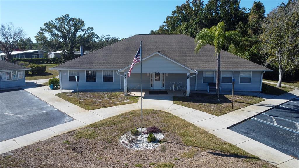 An exterior view of a single-story building with a flag pole and paved walkways — FOREST GLENN DRIVE, SPRING HILL, FL