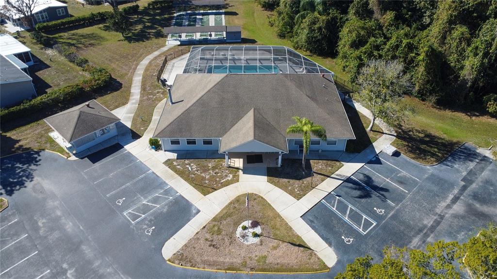 An aerial view shows a community clubhouse with a pool, parking lot, and shuffleboard courts — FOREST GLENN DRIVE, SPRING HILL, FL