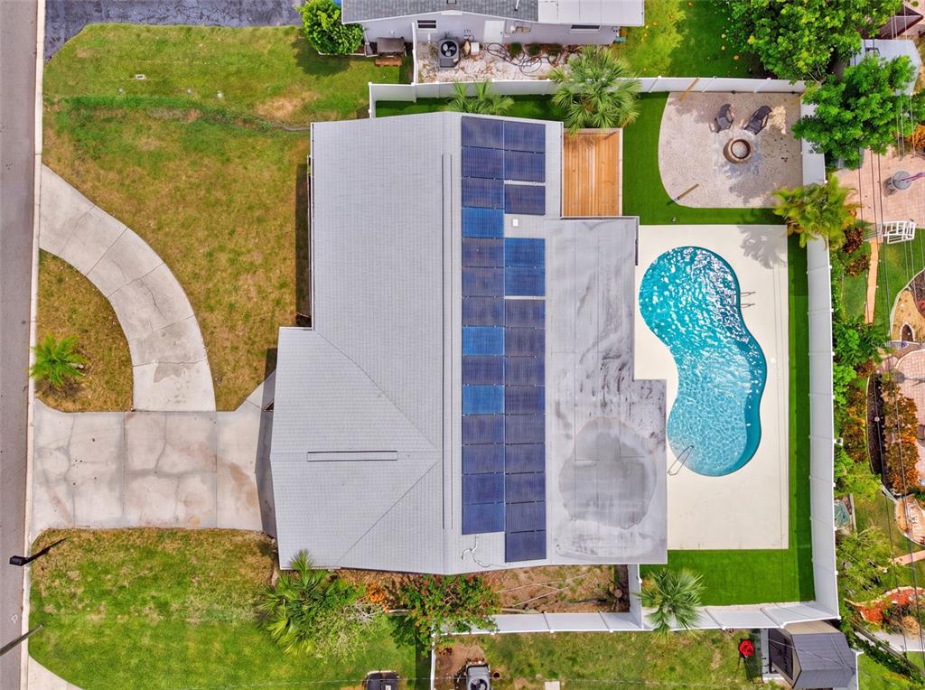 An aerial view shows a house with solar panels, a swimming pool, and a backyard — 3538 SHADY BLUFF DRIVE, LARGO, FL