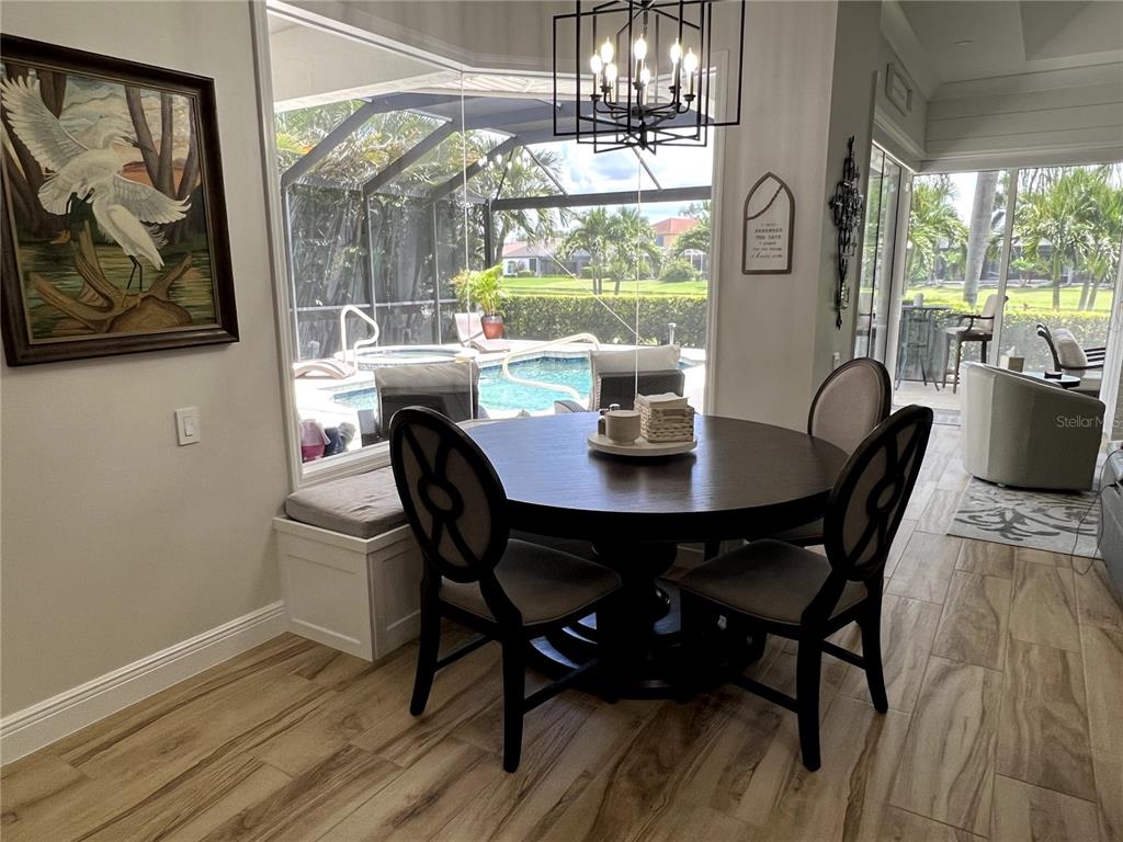 A dining area with a round table and chairs overlooks a pool through large windows — 7555 TORI WAY, BRADENTON, FL