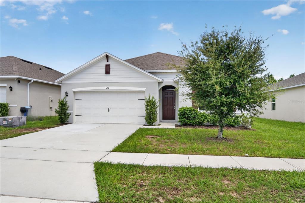 A single-story suburban house with a two-car garage and a concrete driveway — 1292 SUGARWOOD STREET, DAVENPORT, FL