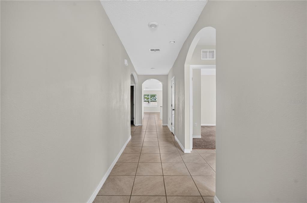 A kitchen features white cabinets, granite countertops, stainless steel appliances, and tile flooring — 1292 SUGARWOOD STREET, DAVENPORT, FL
