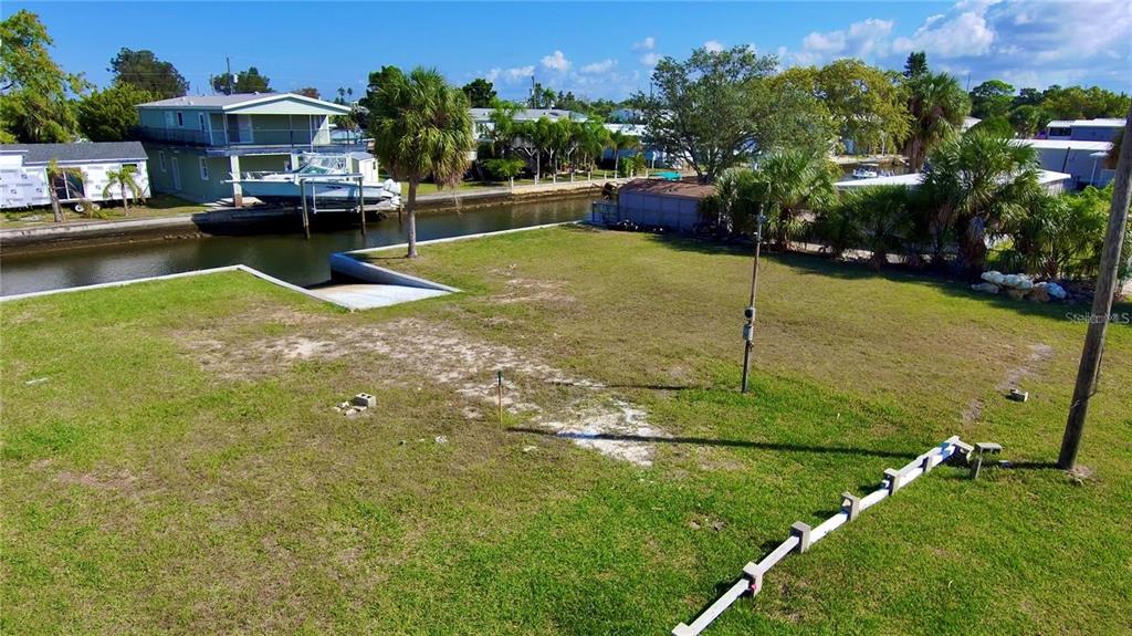 An elevated view of a grassy waterfront lot with a boat ramp and canal — 6731 CURLEW, HUDSON, FL