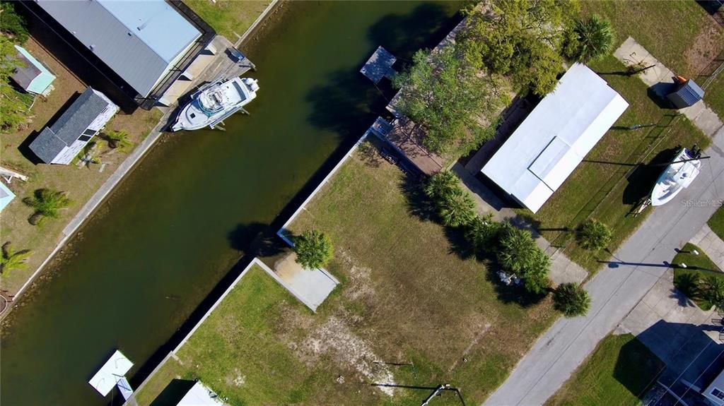 An aerial view shows a vacant waterfront lot with a boat docked in the canal — 6731 CURLEW, HUDSON, FL