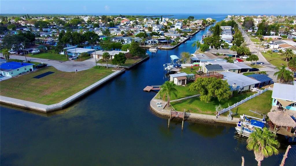 An aerial view shows a residential canal neighborhood with houses, docks, and boats — 6731 CURLEW, HUDSON, FL