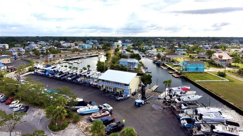 An aerial view shows a marina with boats in slips, a storage building, and parking — 6731 CURLEW, HUDSON, FL