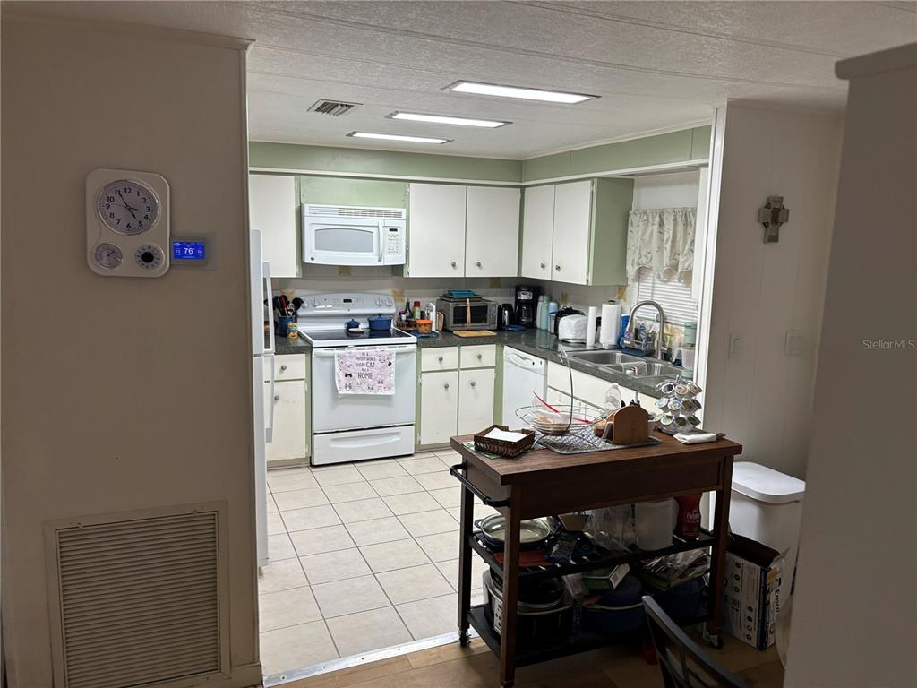 A kitchen features white cabinets, a central wooden island, and tile flooring — 3438 BANBERRY CIRCLE UNIT 1790, ZELLWOOD, FL