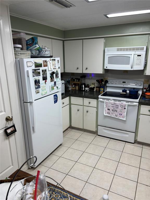 A kitchen with white appliances, white cabinets, and light-colored tile flooring — 3438 BANBERRY CIRCLE UNIT 1790, ZELLWOOD, FL