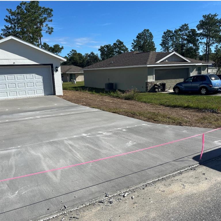 A view of a concrete driveway leading to a house with a two-car garage — 24492 NW HEMLOCK AVENUE, DUNNELLON, FL