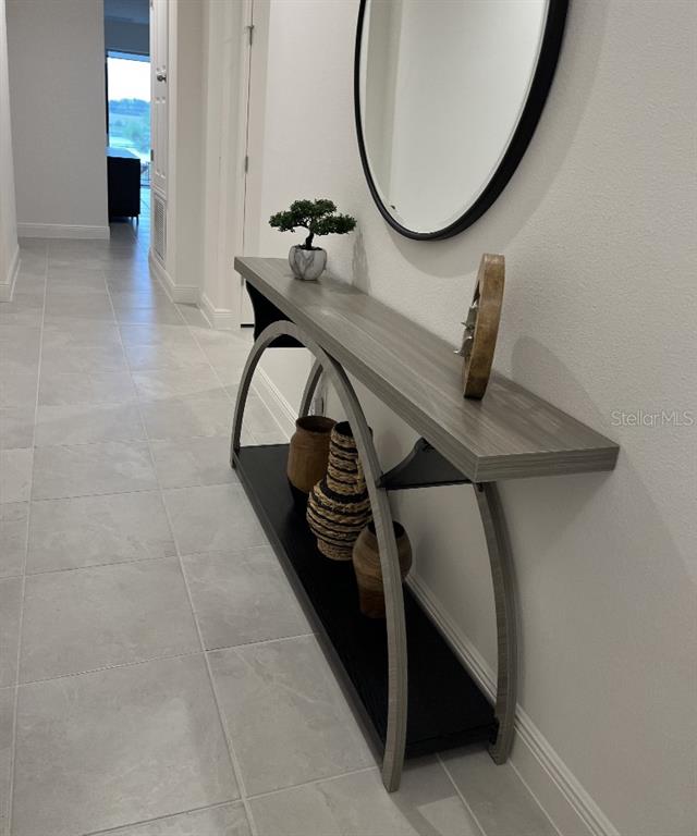 A hallway features a modern console table with a decorative mirror and tiled flooring — 7118 ROLLING LEAF ROAD, GROVELAND, FL