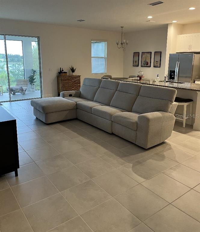 A spacious open-concept living area features a large grey sectional sofa and tiled flooring — 7118 ROLLING LEAF ROAD, GROVELAND, FL