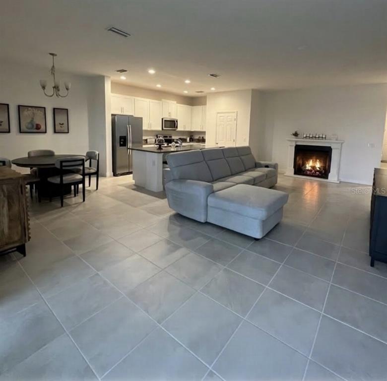 An open-concept living area features a kitchen, dining space, gray sectional, and a fireplace — 7118 ROLLING LEAF ROAD, GROVELAND, FL