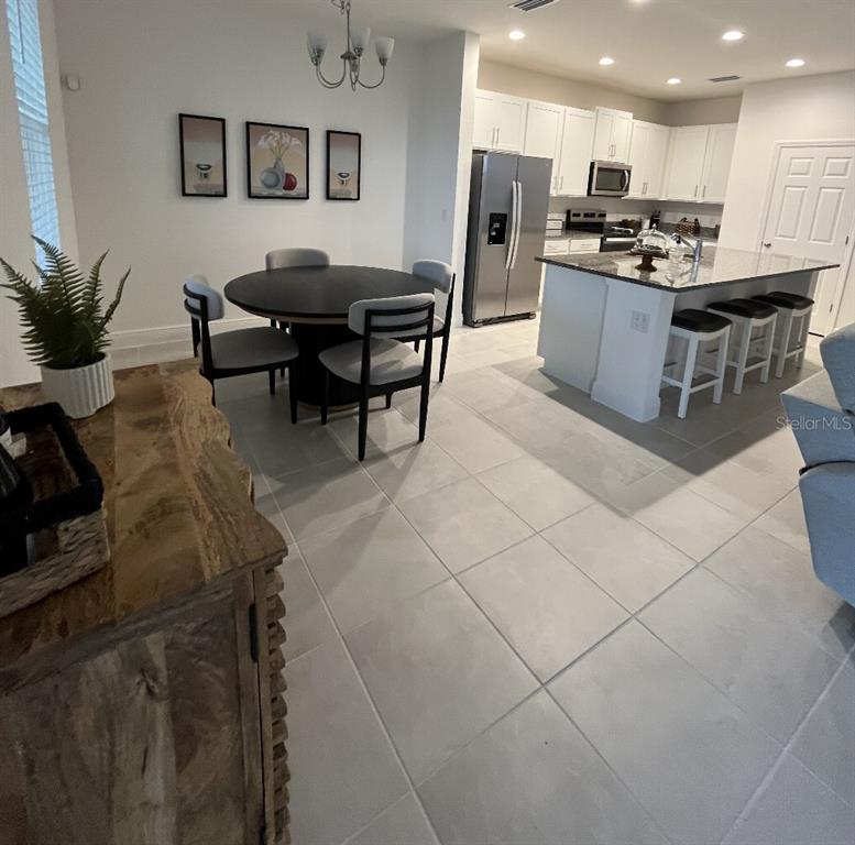 A dining area with a round table and a kitchen featuring white cabinets and an island — 7118 ROLLING LEAF ROAD, GROVELAND, FL
