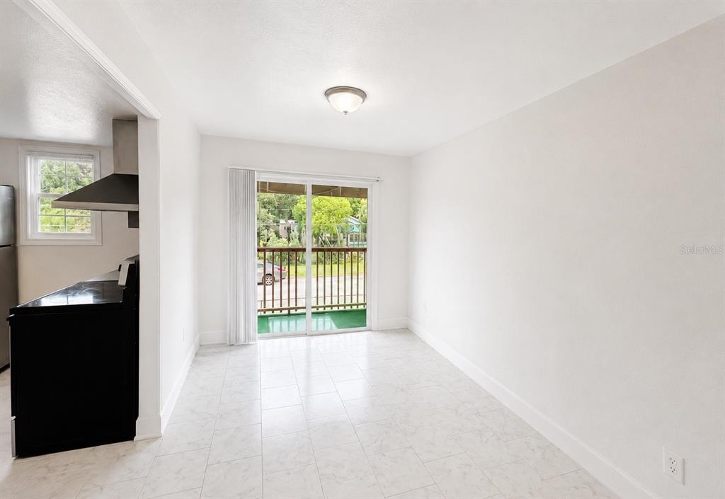 A dining area with white tile floors, a sliding glass door, and an adjacent kitchen — 2751 L B MCLEOD ROAD UNIT 2751, ORLANDO, FL