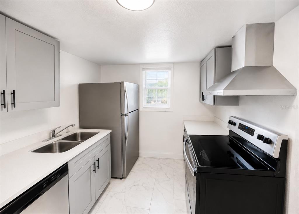 A galley kitchen features gray cabinets, stainless steel appliances, white countertops, and light tile flooring — 2751 L B MCLEOD ROAD UNIT 2751, ORLANDO, FL