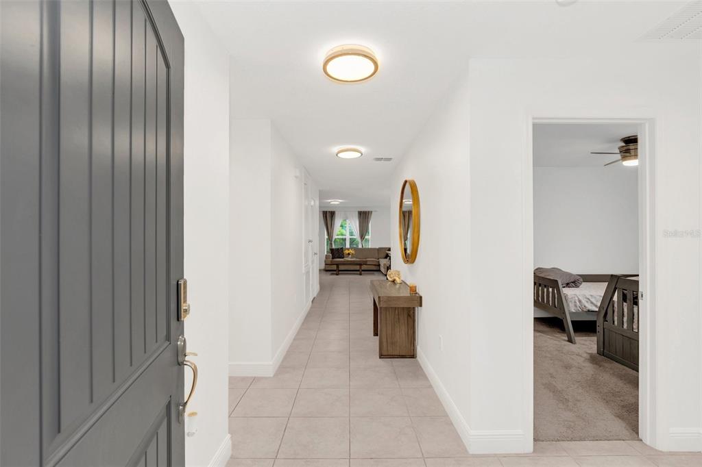 A tiled entryway leads down a hallway toward a living area with a bedroom adjacent — 1877 RIVER CREST AVENUE, ST CLOUD, FL