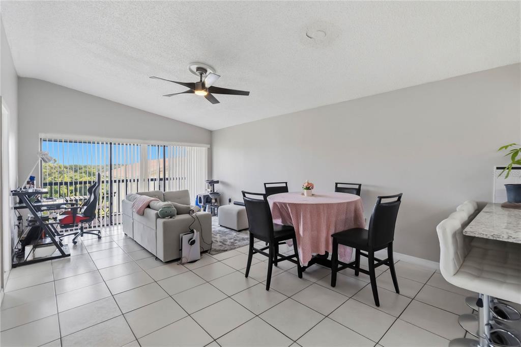 An open-concept living and dining area with tile flooring, a ceiling fan, and sliding glass doors — 1064 LOTUS PARKWAY UNIT 941, ALTAMONTE SPRINGS, FL