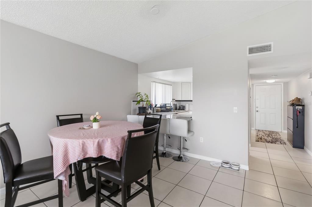 A dining area with a round table, chairs, and a breakfast bar overlooking the kitchen — 1064 LOTUS PARKWAY UNIT 941, ALTAMONTE SPRINGS, FL