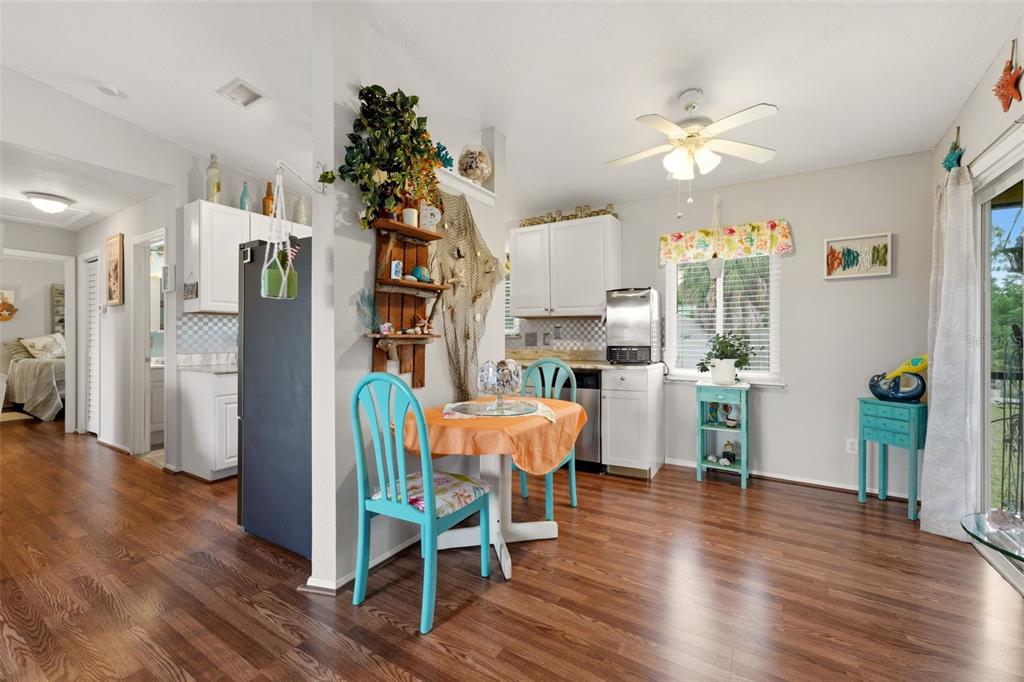 A dining area with a small table, turquoise chairs, and a kitchen in the background — 10182 GULFSTREAM BOULEVARD, ENGLEWOOD, FL