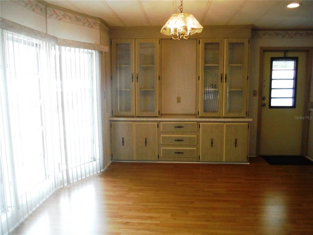A dining room features wood-look flooring, a built-in hutch, a chandelier, and sliding glass doors — 30 STAG RUN COURT UNIT 11, SAFETY HARBOR, FL