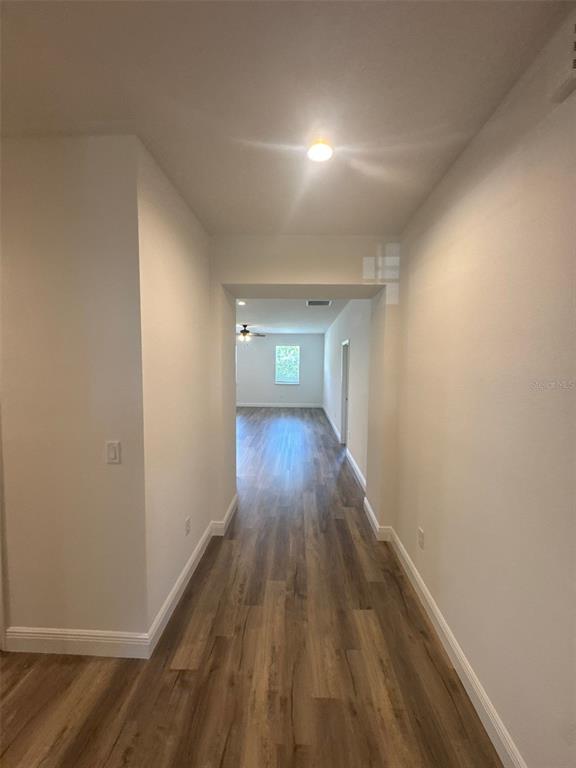 A hallway with wood-look flooring leads to an open living area with a ceiling fan — 531 ELLIE COURT, APOPKA, FL