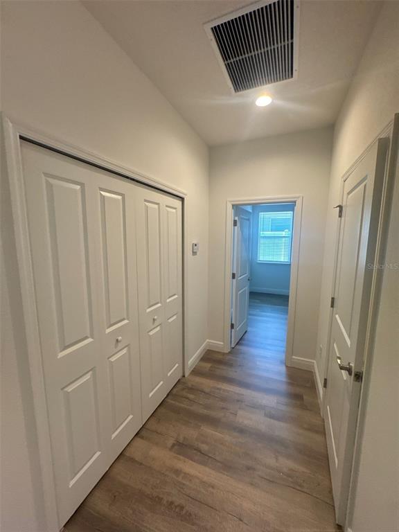 A hallway with wood-look flooring features a white bi-fold closet and a doorway to another room — 531 ELLIE COURT, APOPKA, FL