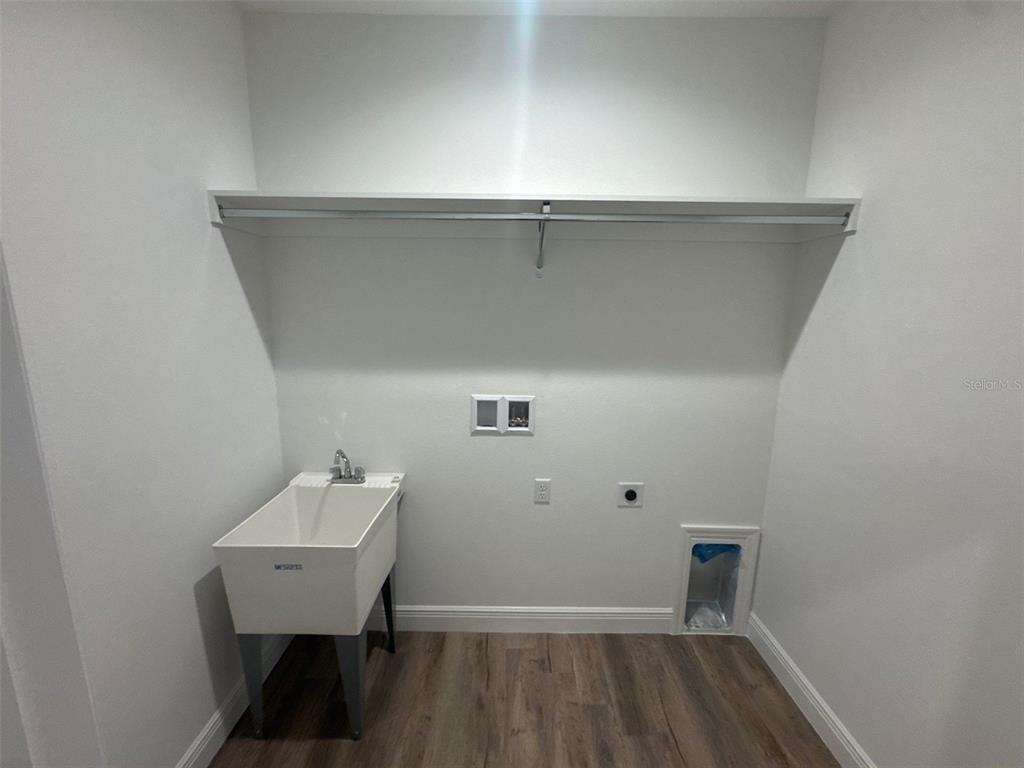 A laundry room features a utility sink, a wall-mounted shelf, and connections for appliances — 531 ELLIE COURT, APOPKA, FL