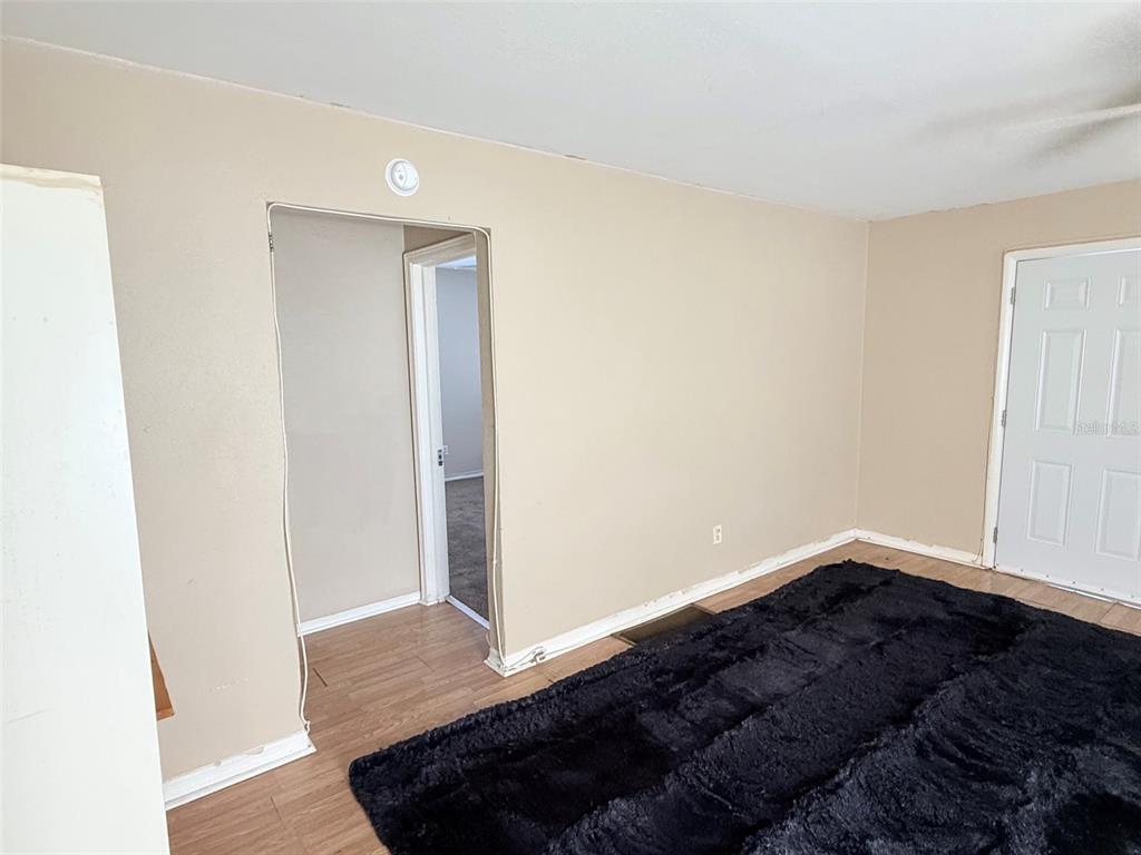 An empty room features tan walls, wood-look flooring, a ceiling fan, and a white door — 986 22ND AVENUE S UNIT 3, ST PETERSBURG, FL