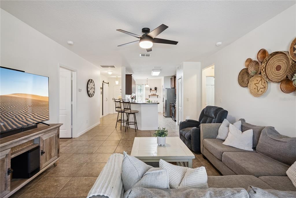 A living room with tile floors, a gray sectional sofa, and an open kitchen area — 2440 VINEYARD CIRCLE, SANFORD, FL