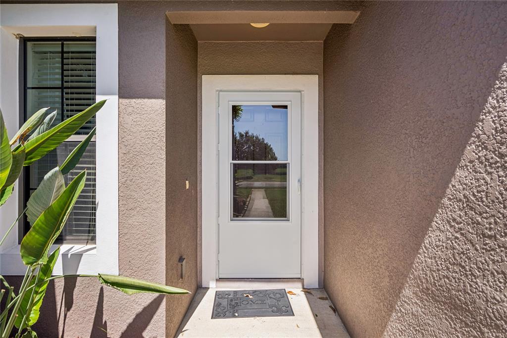 A white storm door is centered in a recessed entryway with tan stucco walls — 2440 VINEYARD CIRCLE, SANFORD, FL