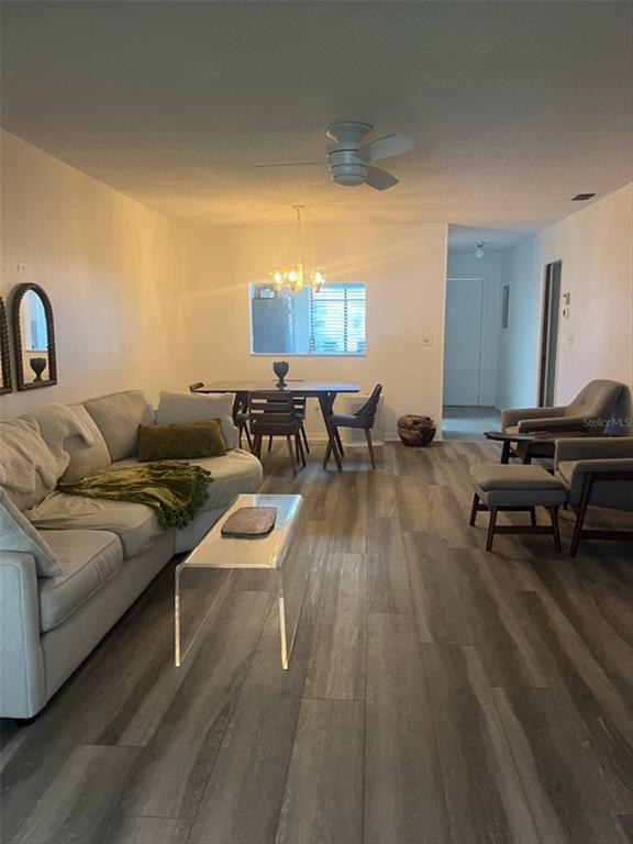 A living room and dining area feature wood-look flooring, a ceiling fan, and neutral walls — 10706 LAQUINTA DRIVE, NEW PORT RICHEY, FL