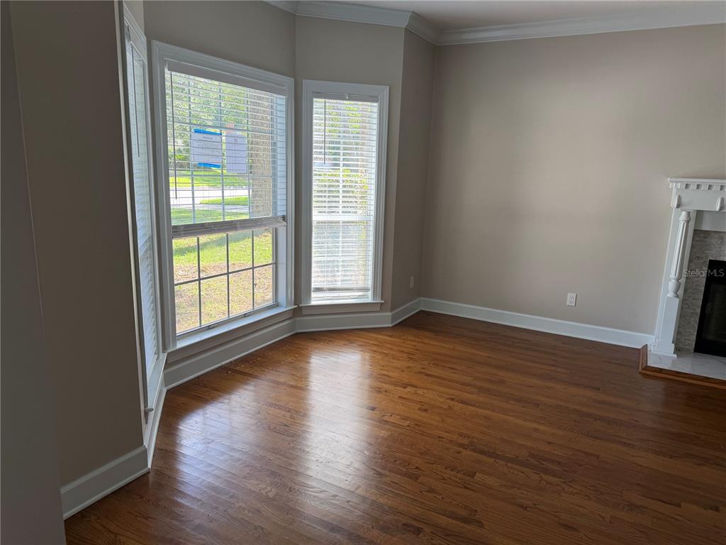 A living room features hardwood floors, a bay window with blinds, and a white fireplace — 916 HILLCREST COURT, TALLAHASSEE, FL