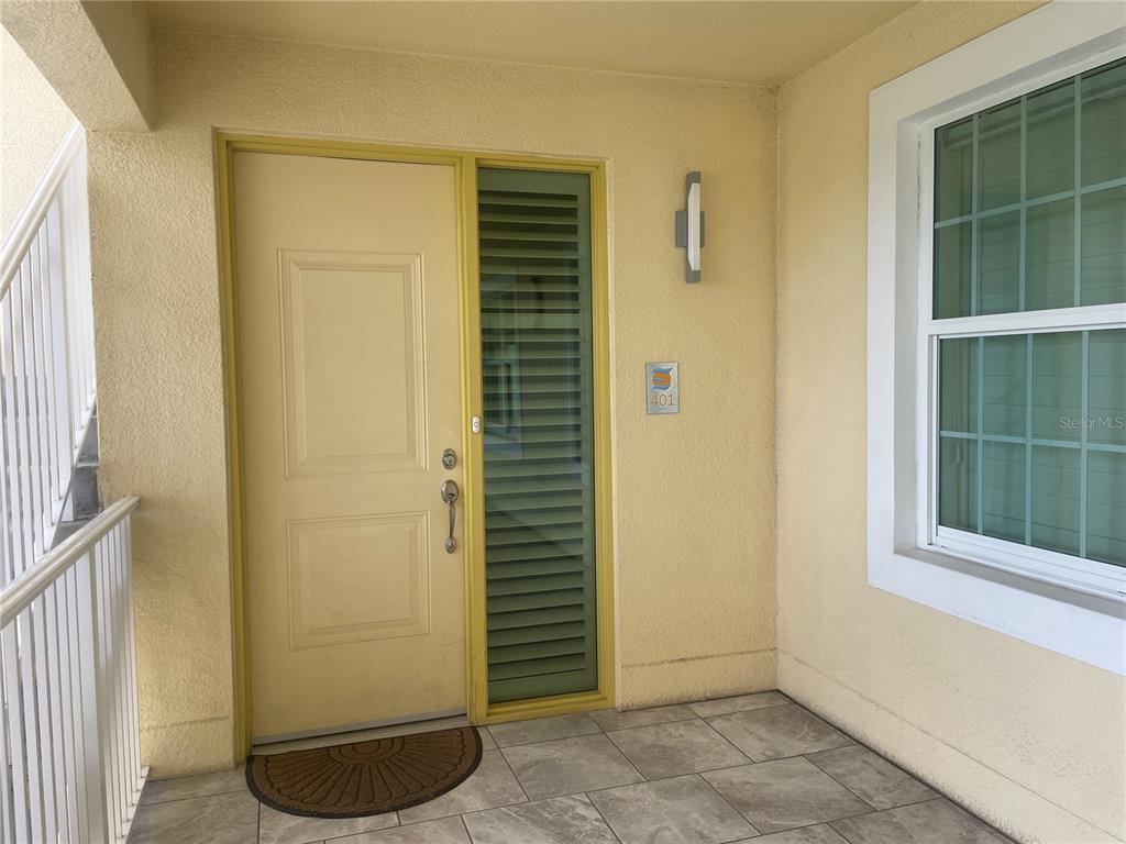 A light yellow front door with a side window and tiled porch area — 260 HIDDEN BAY DRIVE UNIT 401, OSPREY, FL