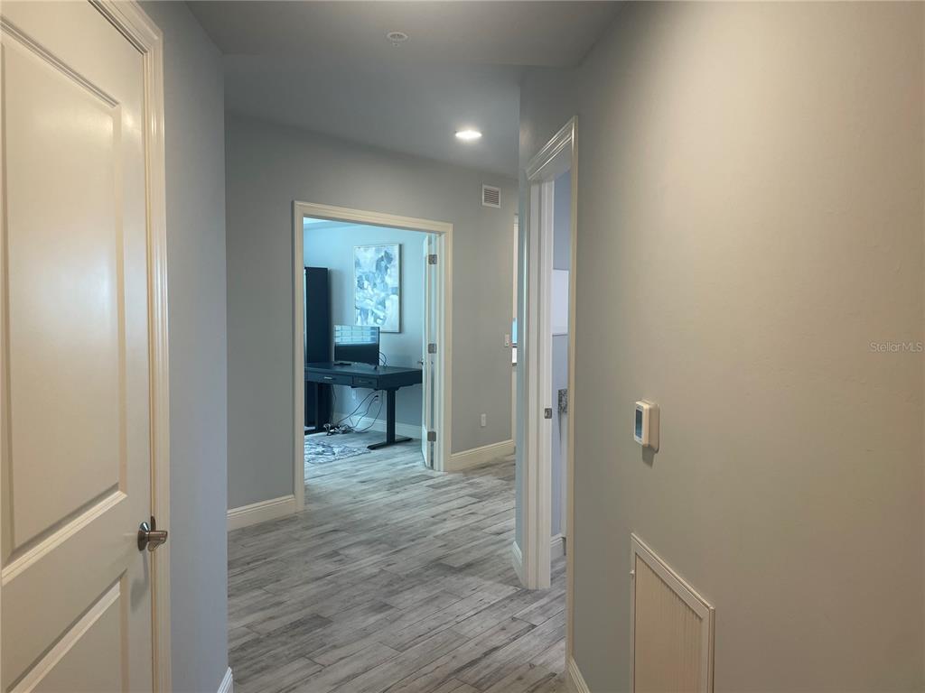 A hallway with light gray walls, wood-look tile flooring, and two open doorways — 260 HIDDEN BAY DRIVE UNIT 401, OSPREY, FL