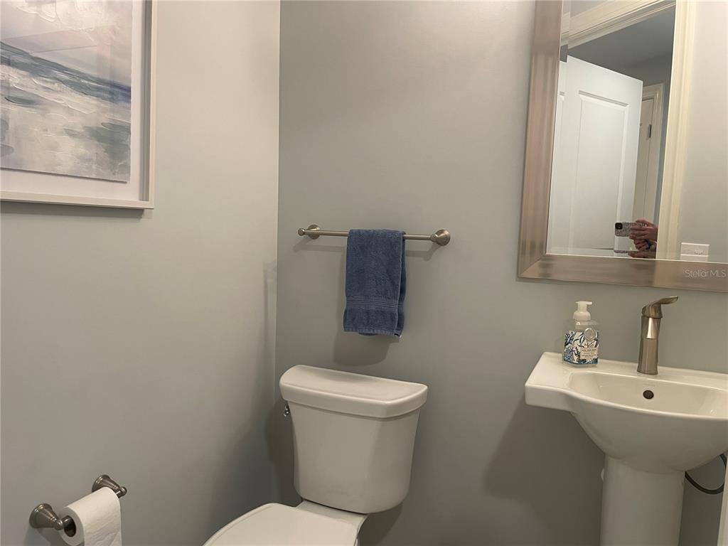 A bathroom features a pedestal sink, a toilet, a towel rack, and wall art — 260 HIDDEN BAY DRIVE UNIT 401, OSPREY, FL