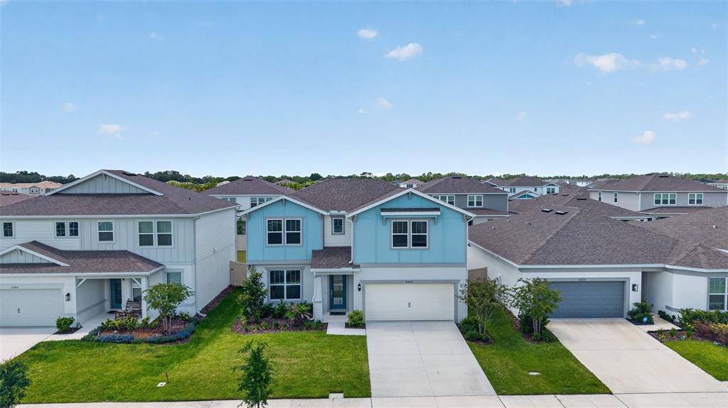 A two-story blue house with a white garage sits between two neighboring suburban homes — 6036 FOREST PERCH DRIVE, ST CLOUD, FL