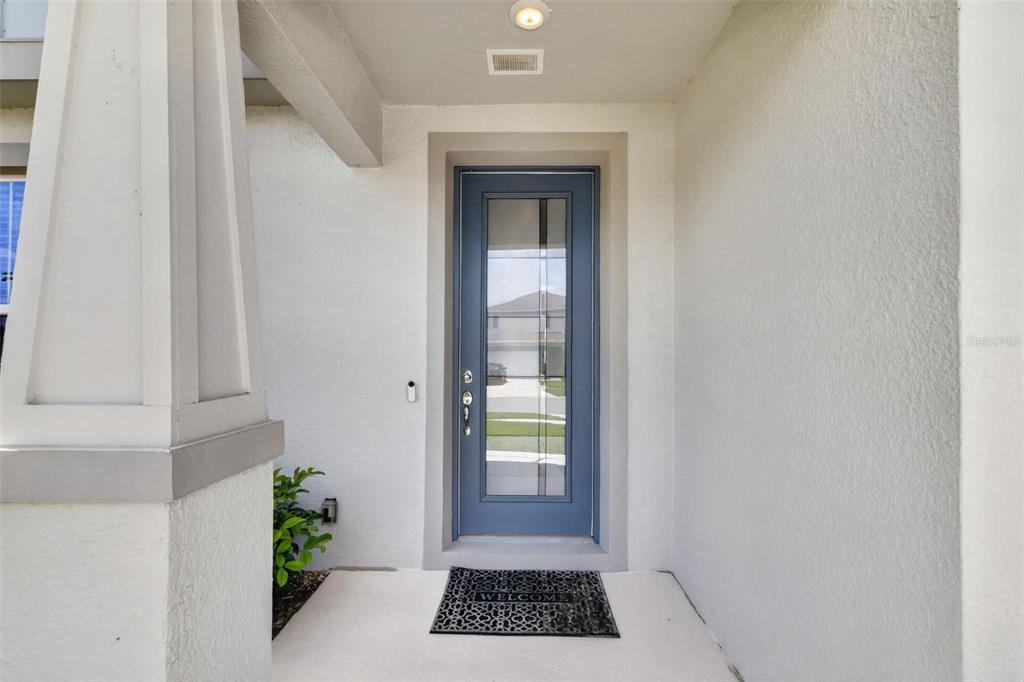 A blue front door with a glass panel sits under a covered entryway — 6036 FOREST PERCH DRIVE, ST CLOUD, FL